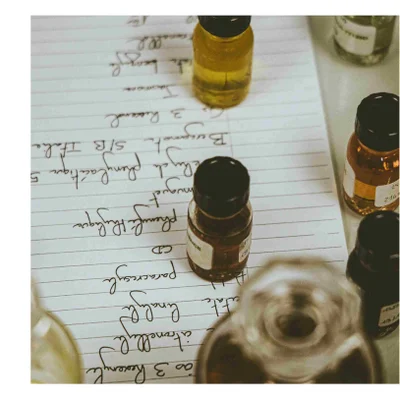 Small glass bottles containing liquids sit on a sheet of paper with handwritten notes including 3 Resorcin Citronellol Linalool Paracresol CD Phenylactique muguet Eucalyptus Phénylacétique 5 Bergamot 3 Ris Italia S/B Jakon th benzyle 24 NCE.