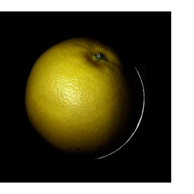 A yellow grapefruit is shown against a dark background with a highlight on the right edge.