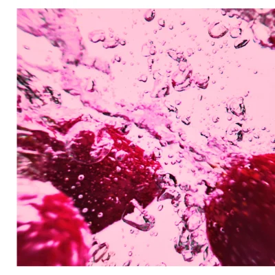 Close-up abstract view of red objects submerged in bubbly pink liquid.